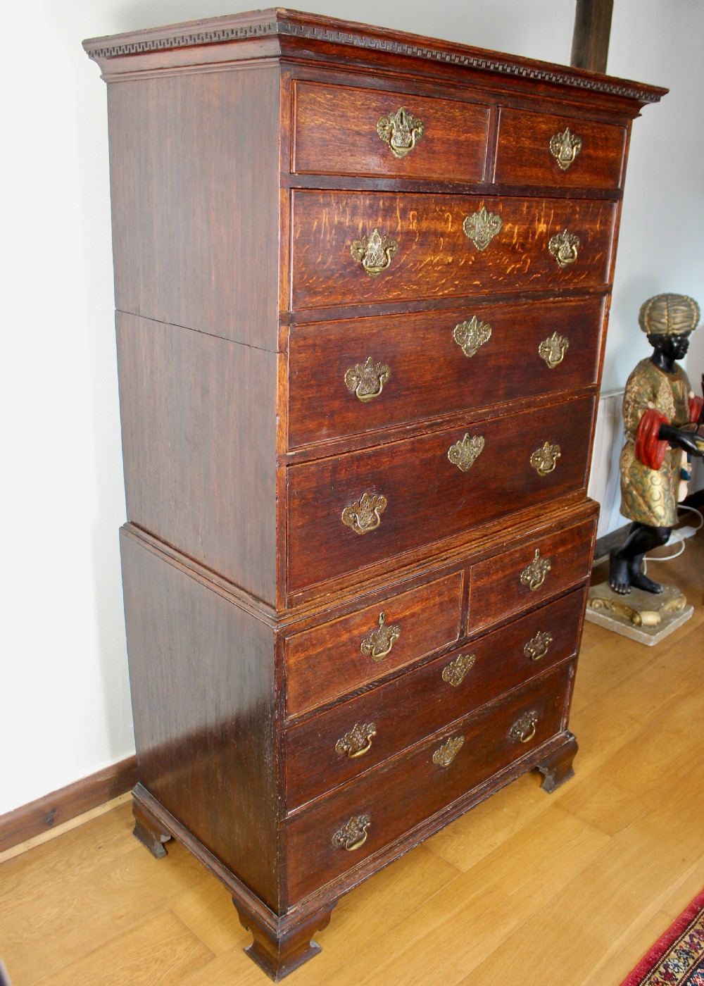 A tall George III dark oak chest-on-chest featuring two short over five long graduated drawers adorned with ornate brass handles and supported on ogee bracket feet. View III