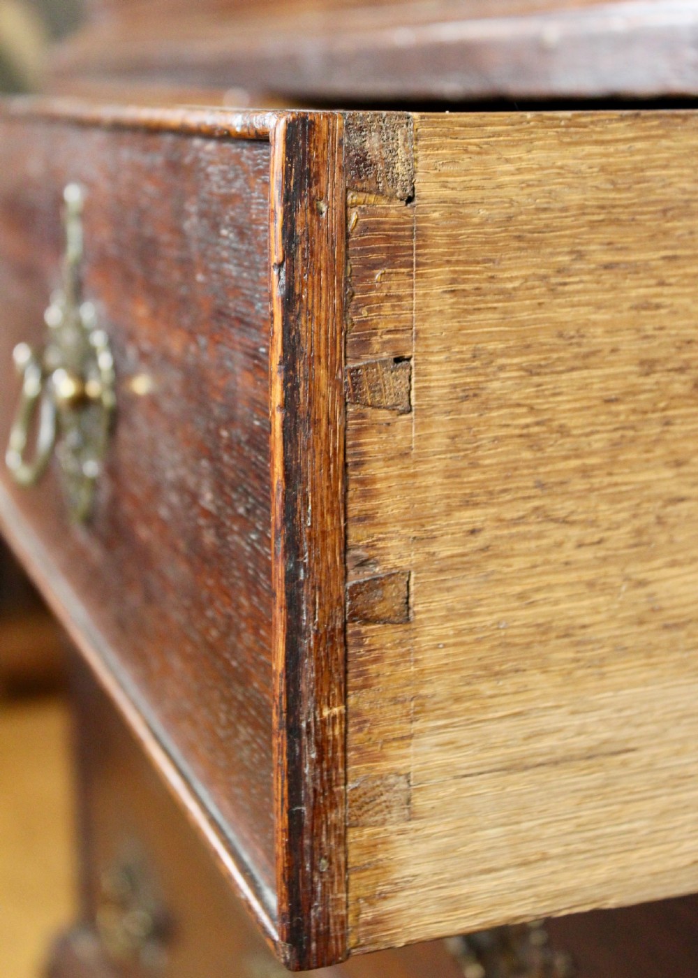 A tall George III dark oak chest-on-chest featuring two short over five long graduated drawers adorned with ornate brass handles and supported on ogee bracket feet. View V