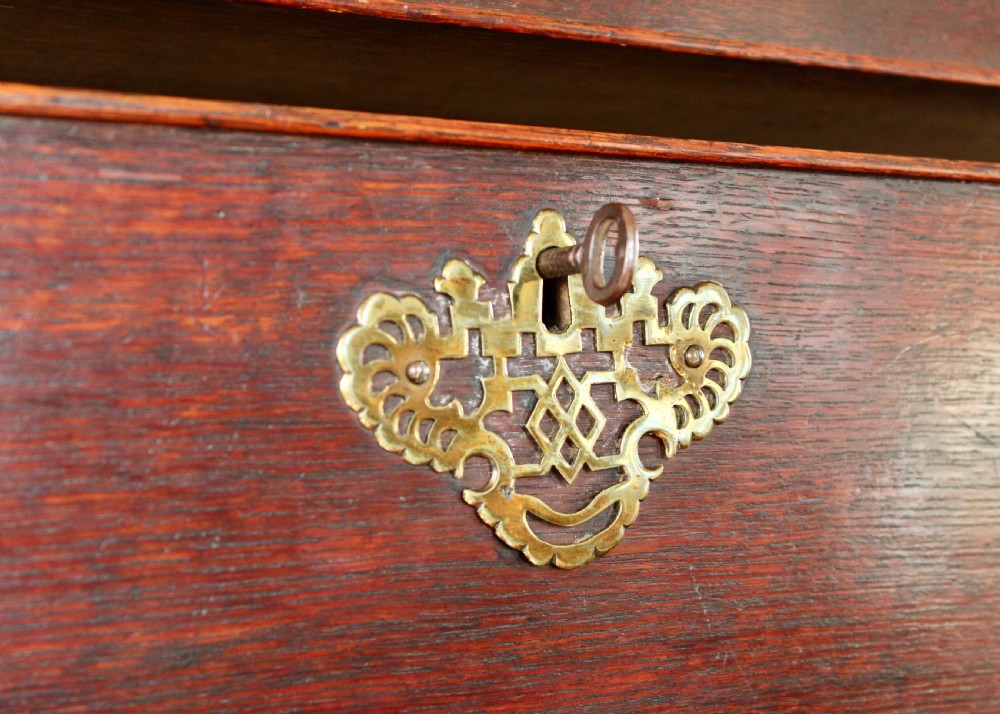 A tall George III dark oak chest-on-chest featuring two short over five long graduated drawers adorned with ornate brass handles and supported on ogee bracket feet. View IX