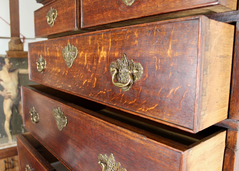A tall George III dark oak chest-on-chest featuring two short over five long graduated drawers adorned with ornate brass handles and supported on ogee bracket feet. View X