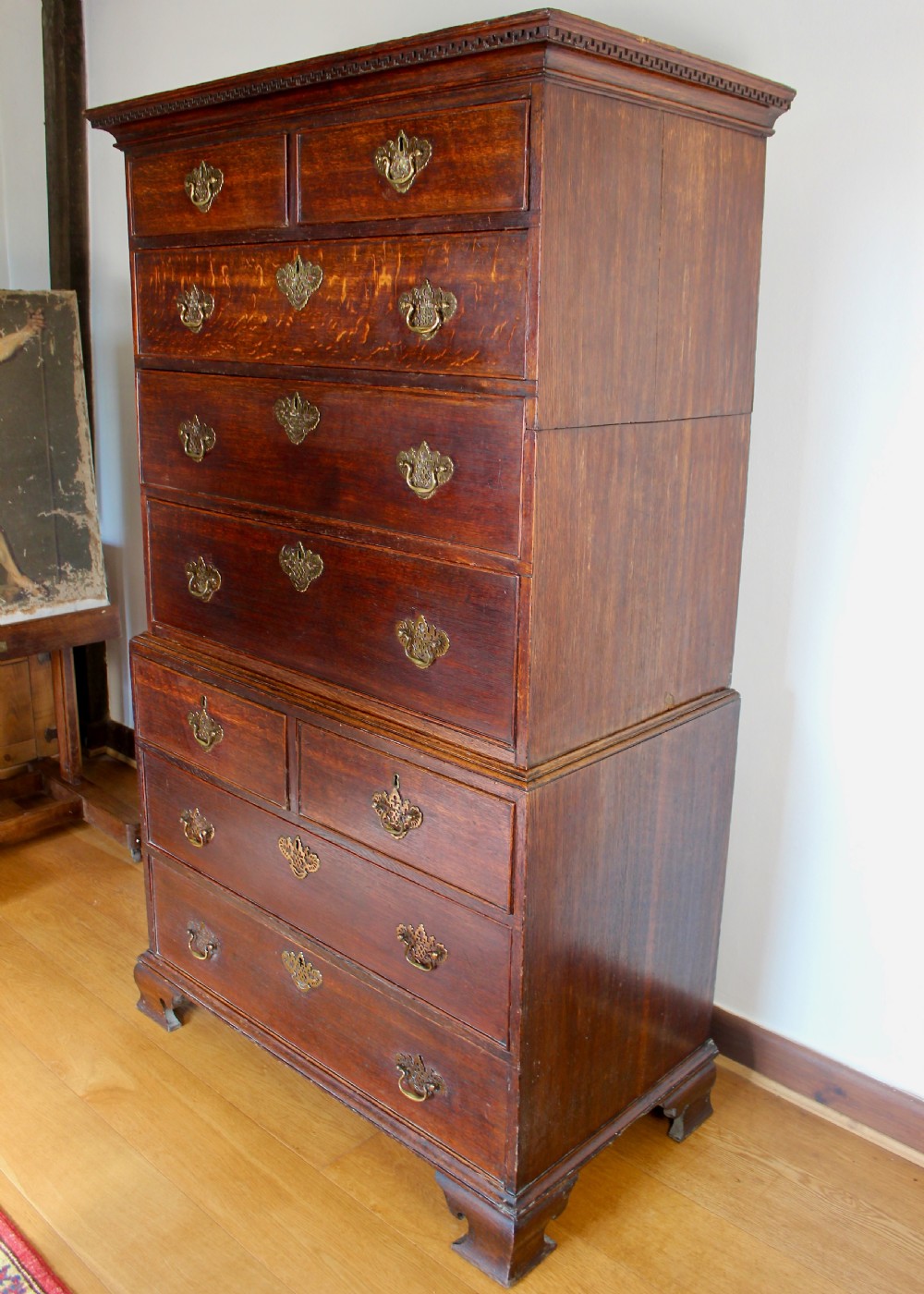 A tall George III dark oak chest-on-chest featuring two short over five long graduated drawers adorned with ornate brass handles and supported on ogee bracket feet. View XII
