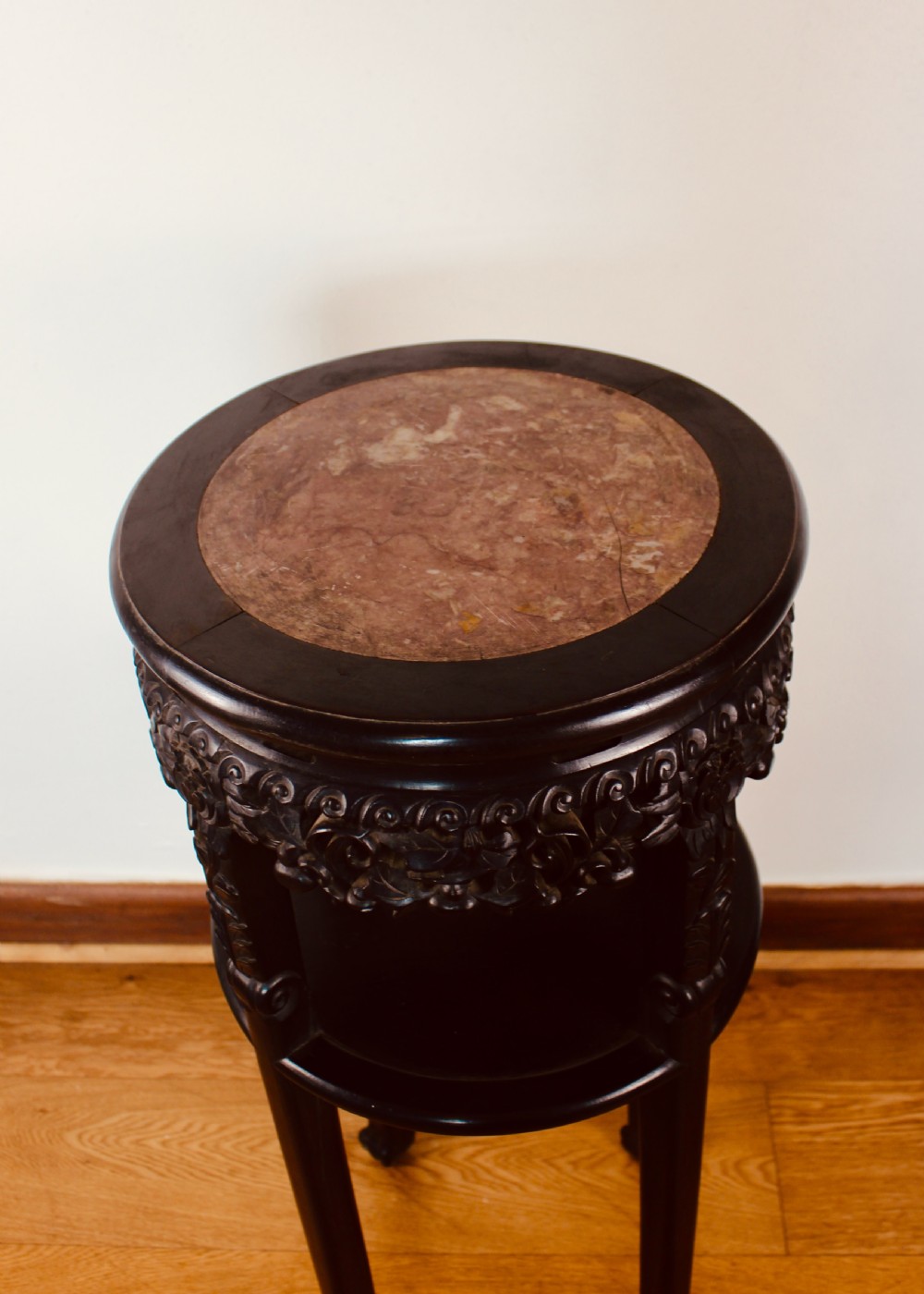 A tall dark hardwood circular jardiniere stand featuring an inset marble top, a pierced carved frieze, a lower circular undertier, and four slender legs. View II