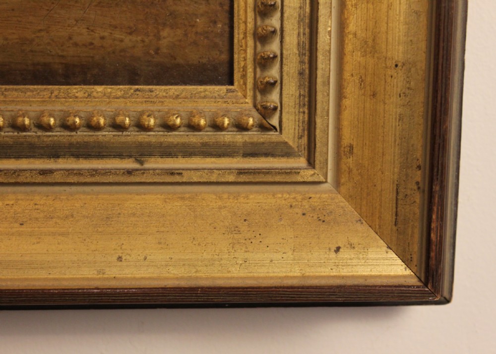 A 19th-century naive oil painting depicting a white and brown cow standing inside a dark stable framed in a gilded timber frame. View II