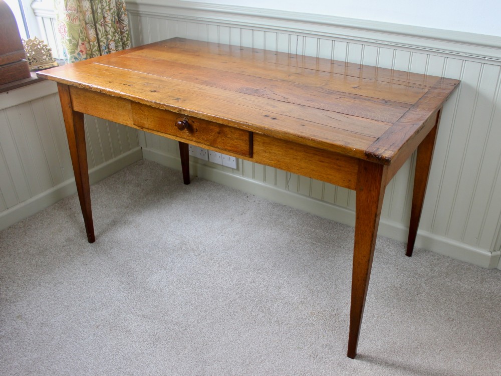 A 19th-century French provincial oak farmhouse table featuring a rectangular plank top, a single frieze drawer with a wooden knob, and four tapered square legs.