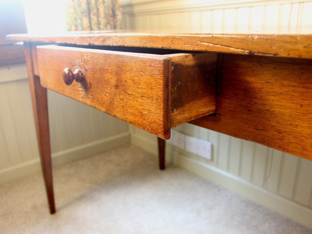 A 19th-century French provincial oak farmhouse table featuring a rectangular plank top, a single frieze drawer with a wooden knob, and four tapered square legs. View IV