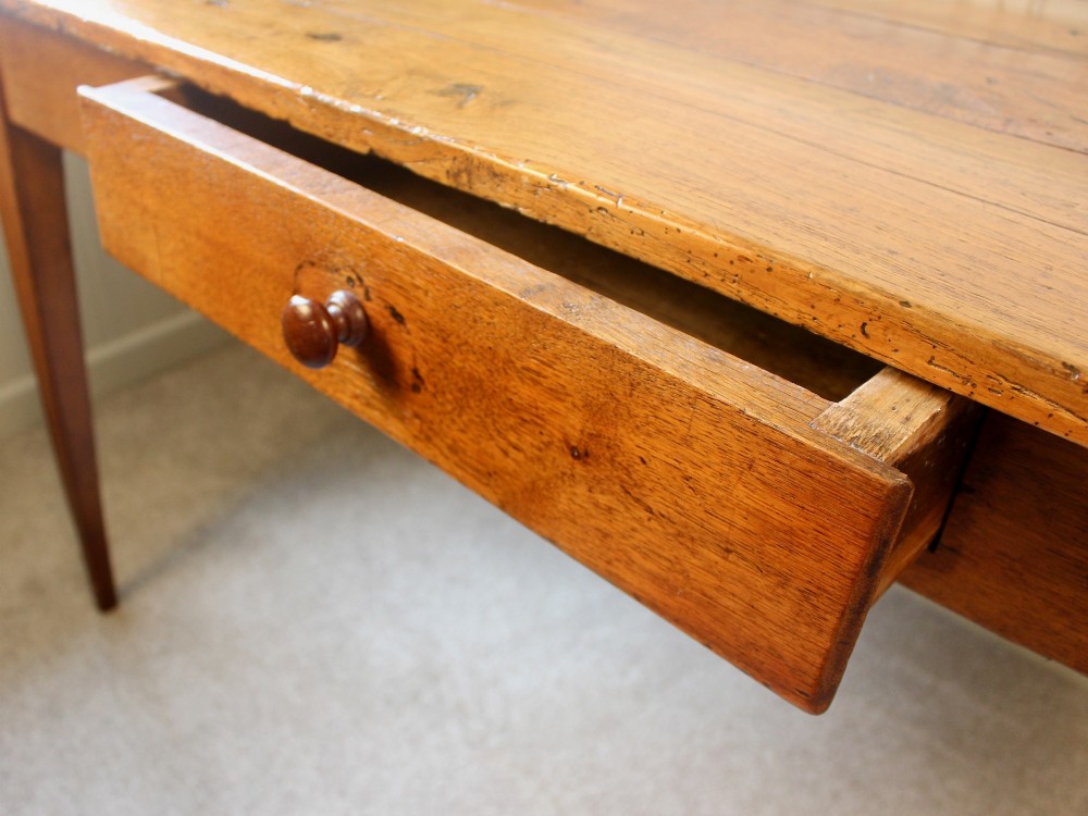 A 19th-century French provincial oak farmhouse table featuring a rectangular plank top, a single frieze drawer with a wooden knob, and four tapered square legs. View V
