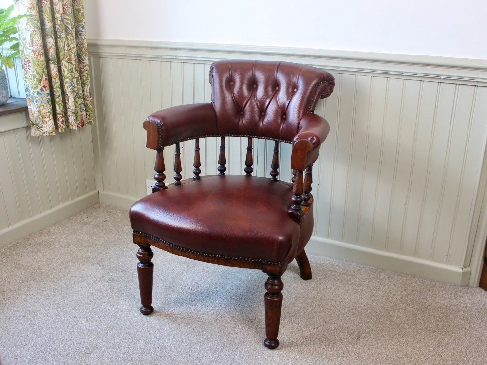 A Victorian oak elbow chair featuring deep buttoned reddish-brown leather upholstery, turned spindles, metal stud trim, and turned front legs. View II