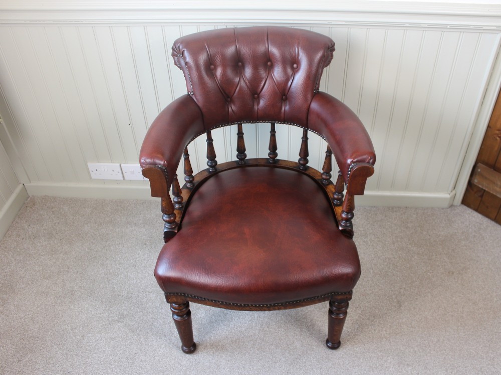 A Victorian oak elbow chair featuring deep buttoned reddish-brown leather upholstery, turned spindles, metal stud trim, and turned front legs. View III