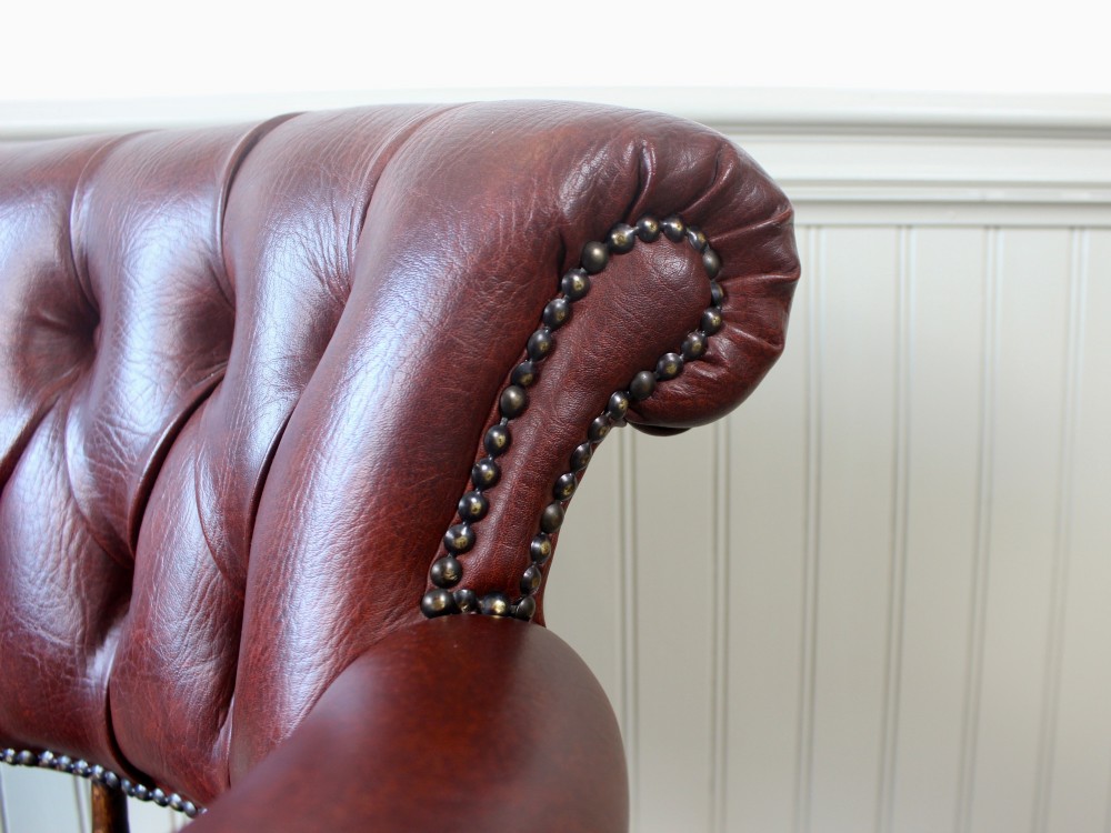 A Victorian oak elbow chair featuring deep buttoned reddish-brown leather upholstery, turned spindles, metal stud trim, and turned front legs. View VIII
