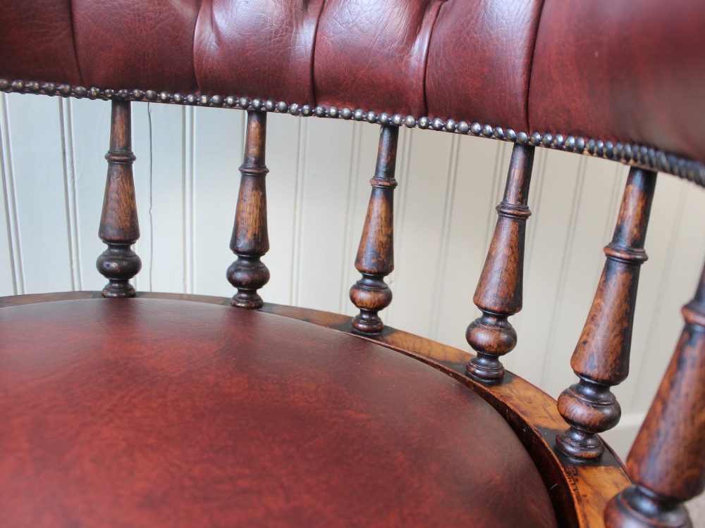 A Victorian oak elbow chair featuring deep buttoned reddish-brown leather upholstery, turned spindles, metal stud trim, and turned front legs. View IX