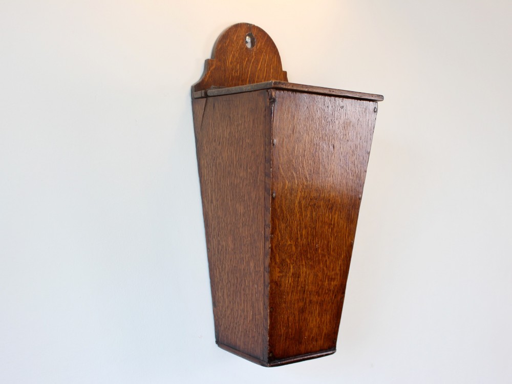 A George III tapered wall-hanging candle box crafted from warm brown oak with an arched crest panel and a top lid. View III