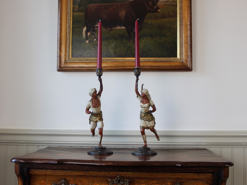 A pair of antique cold-painted spelter figural candlesticks depicting male and female figures in Orientalist attire holding raised torch nozzles. View II