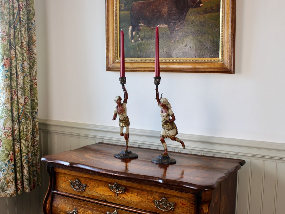 A pair of antique cold-painted spelter figural candlesticks depicting male and female figures in Orientalist attire holding raised torch nozzles. View III