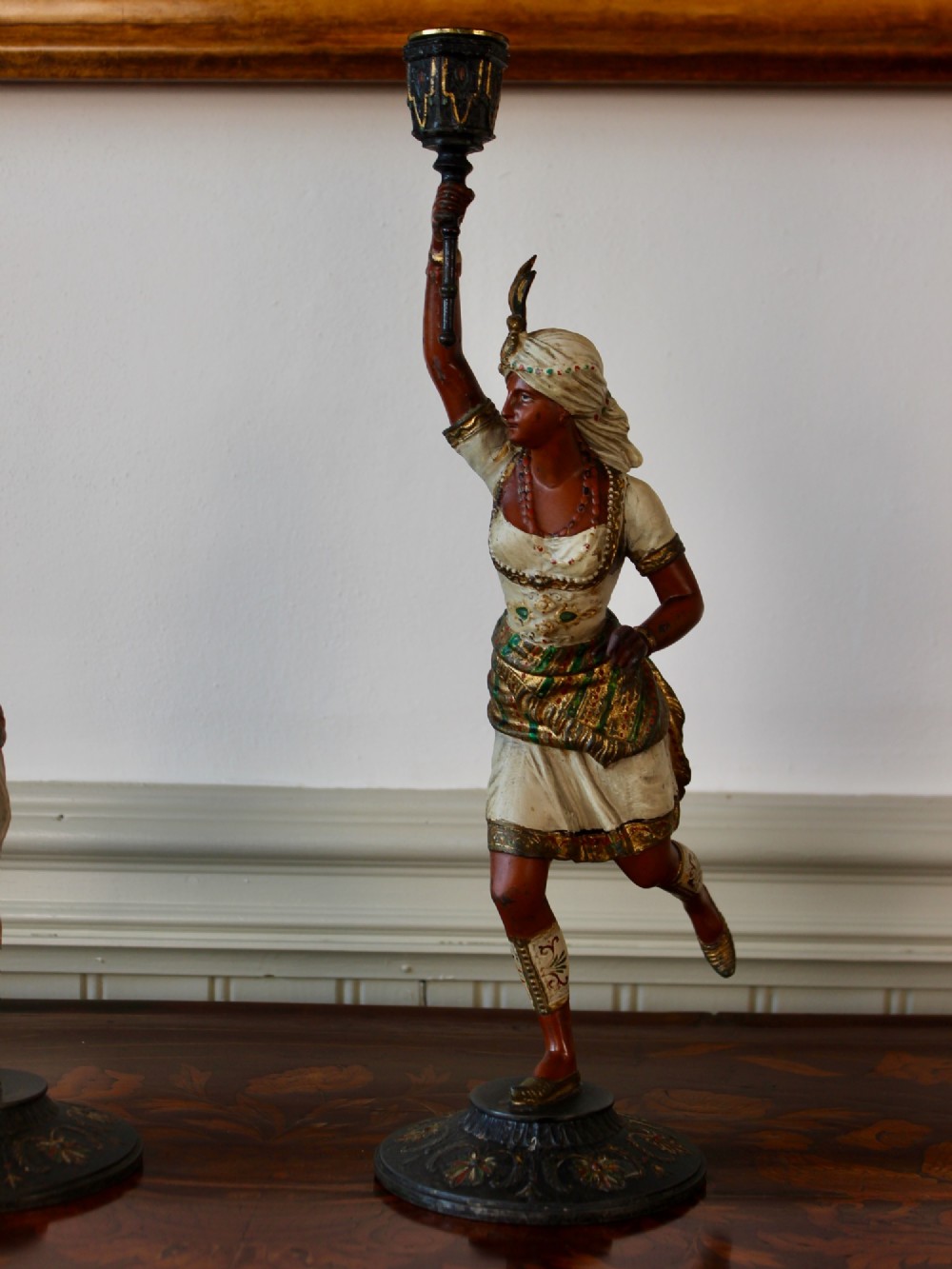 A pair of antique cold-painted spelter figural candlesticks depicting male and female figures in Orientalist attire holding raised torch nozzles. View IV