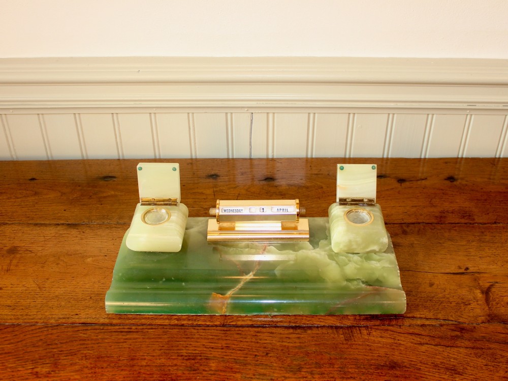 An Art Deco green onyx desk stand featuring a central gilt brass perpetual calendar flanked by two lidded onyx inkwells on a stepped rectangular base with a pen groove. View III