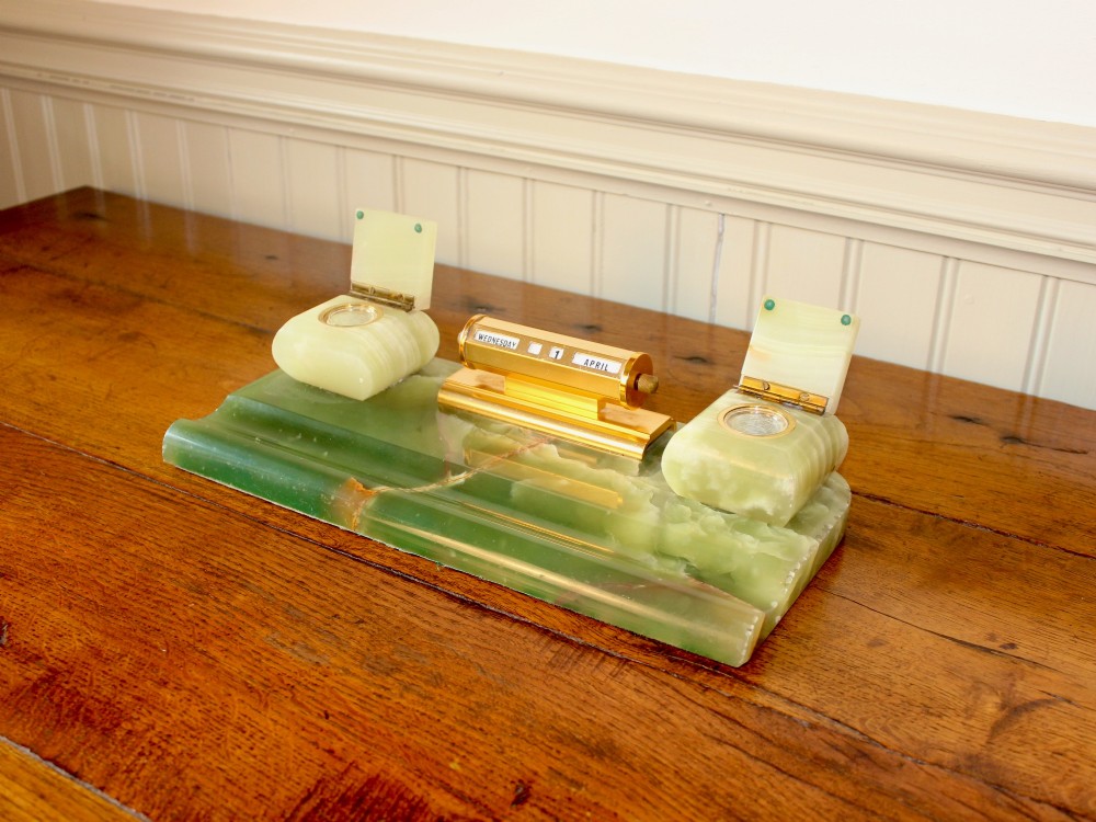 An Art Deco green onyx desk stand featuring a central gilt brass perpetual calendar flanked by two lidded onyx inkwells on a stepped rectangular base with a pen groove. View IV