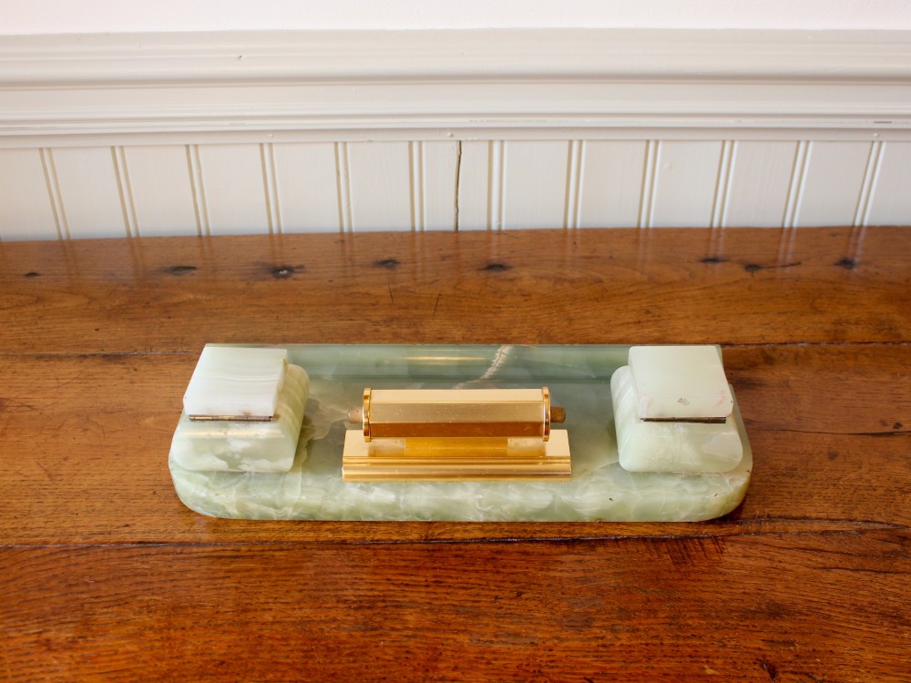An Art Deco green onyx desk stand featuring a central gilt brass perpetual calendar flanked by two lidded onyx inkwells on a stepped rectangular base with a pen groove. View VI