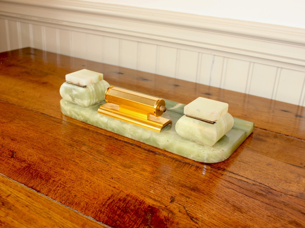 An Art Deco green onyx desk stand featuring a central gilt brass perpetual calendar flanked by two lidded onyx inkwells on a stepped rectangular base with a pen groove. View VII