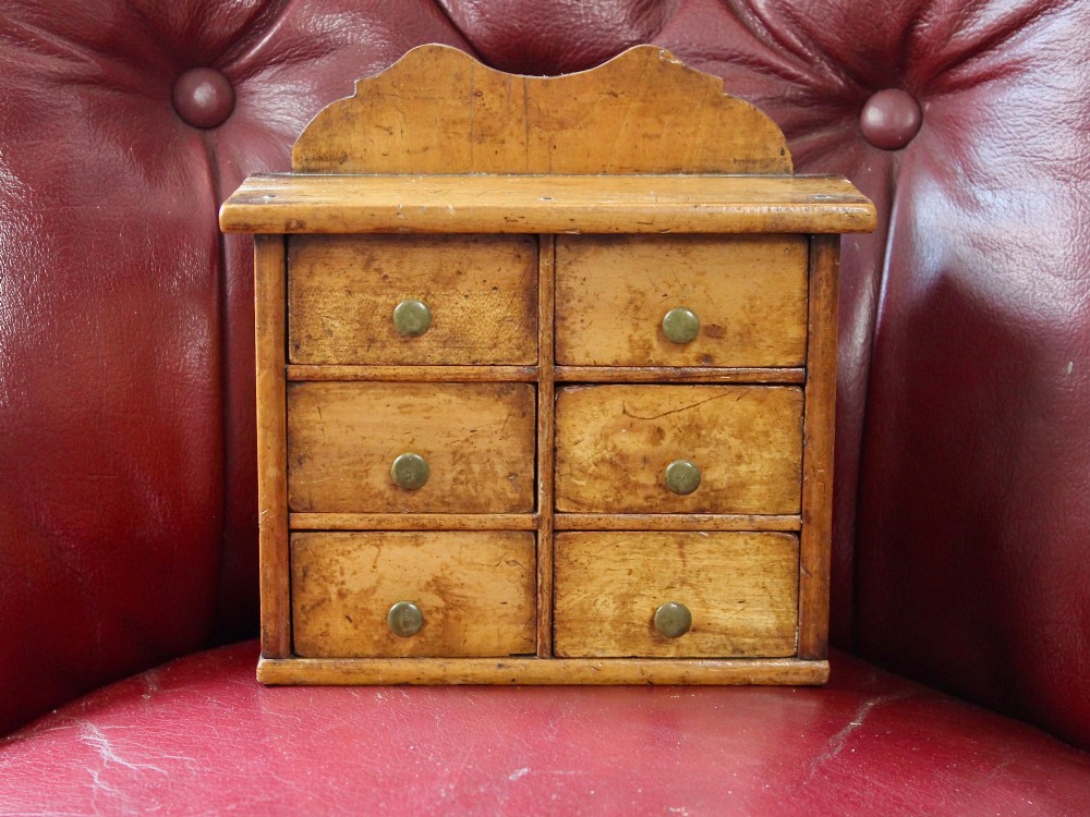 A small 19th-century fruitwood spice chest featuring six individual drawers with small brass knobs and a shaped back gallery. View II