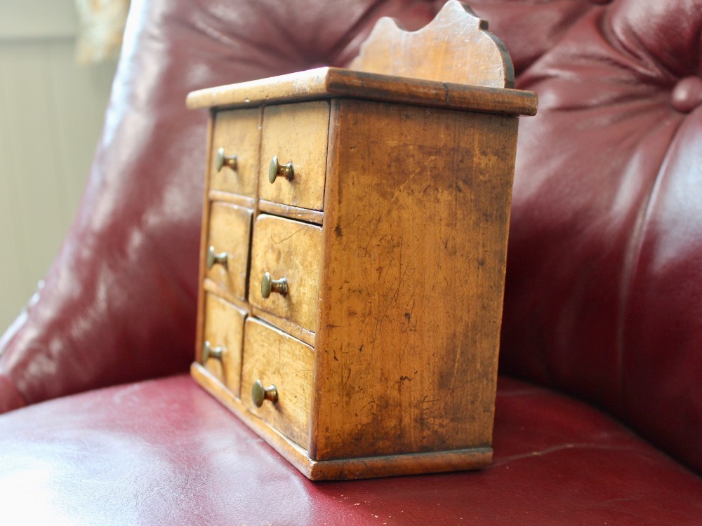 A small 19th-century fruitwood spice chest featuring six individual drawers with small brass knobs and a shaped back gallery. View V