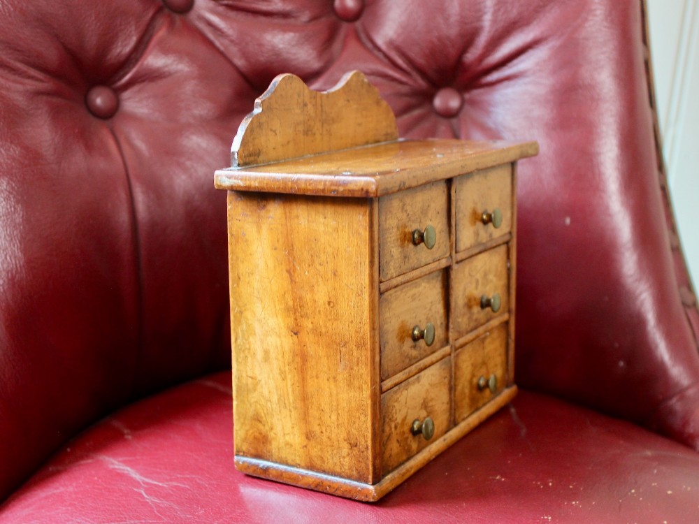 A small 19th-century fruitwood spice chest featuring six individual drawers with small brass knobs and a shaped back gallery. View VII