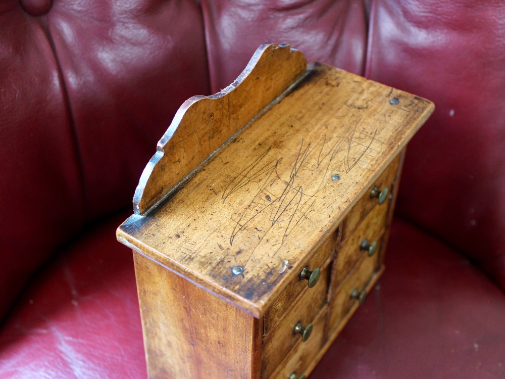 A small 19th-century fruitwood spice chest featuring six individual drawers with small brass knobs and a shaped back gallery. View VIII