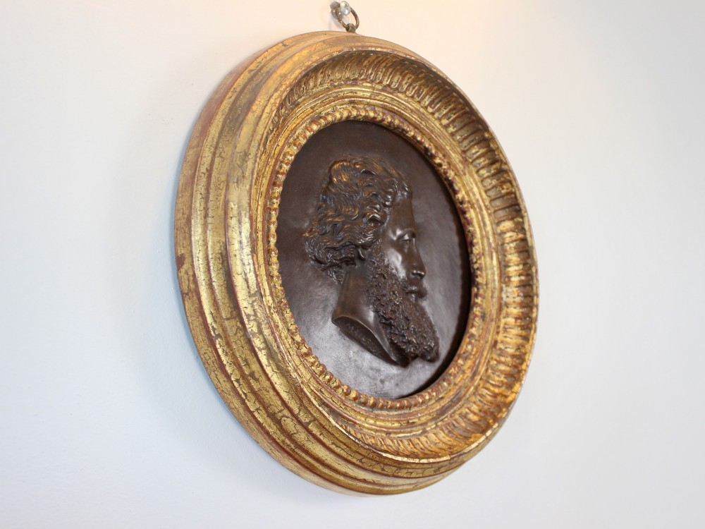 A circular 19th-century bronze bas-relief portrait plaque depicting a gentleman with a full beard in side profile, mounted in a gilded round frame.
