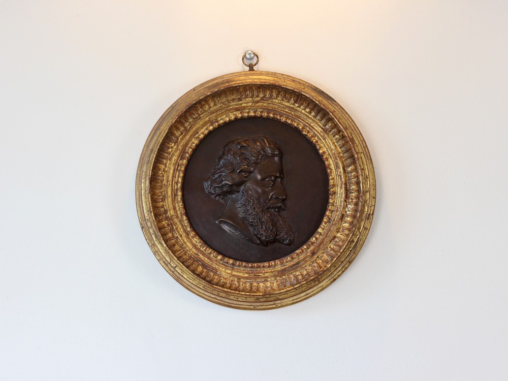 A circular 19th-century bronze bas-relief portrait plaque depicting a gentleman with a full beard in side profile, mounted in a gilded round frame. View II