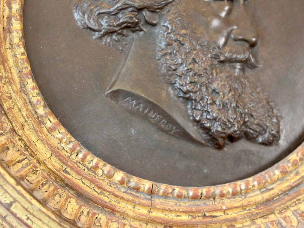 A circular 19th-century bronze bas-relief portrait plaque depicting a gentleman with a full beard in side profile, mounted in a gilded round frame. View III