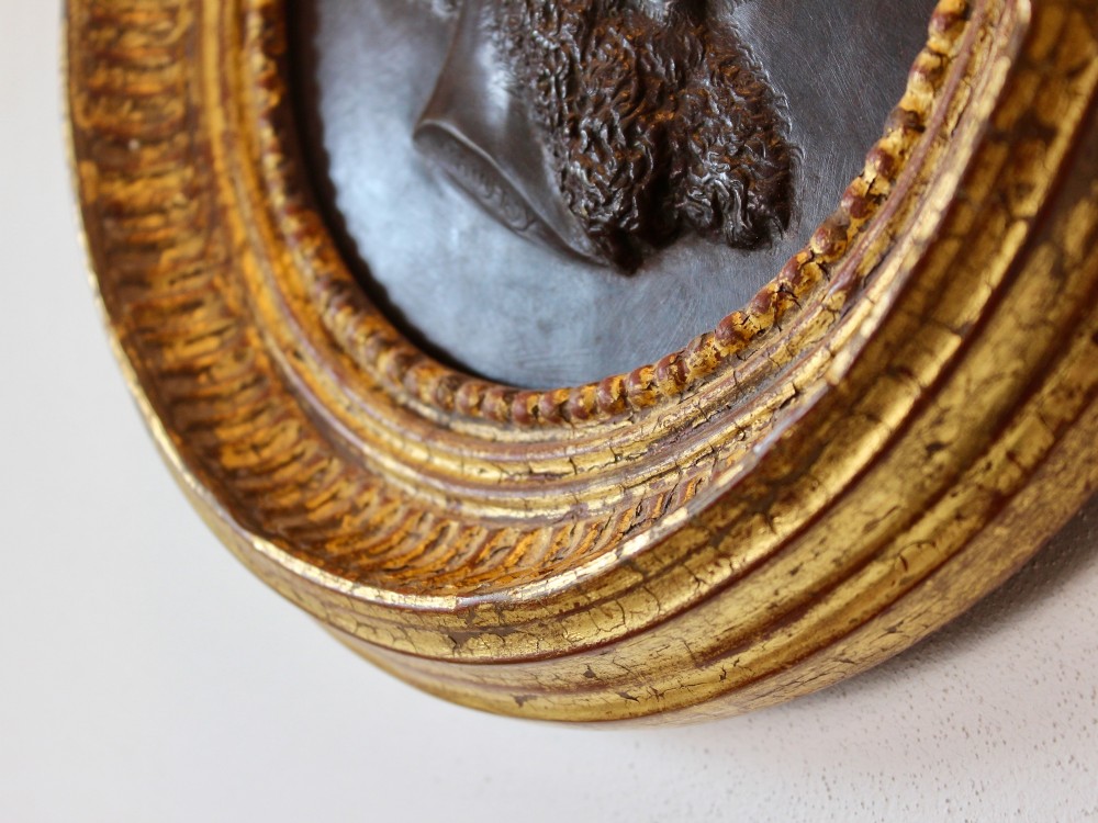 A circular 19th-century bronze bas-relief portrait plaque depicting a gentleman with a full beard in side profile, mounted in a gilded round frame. View IV