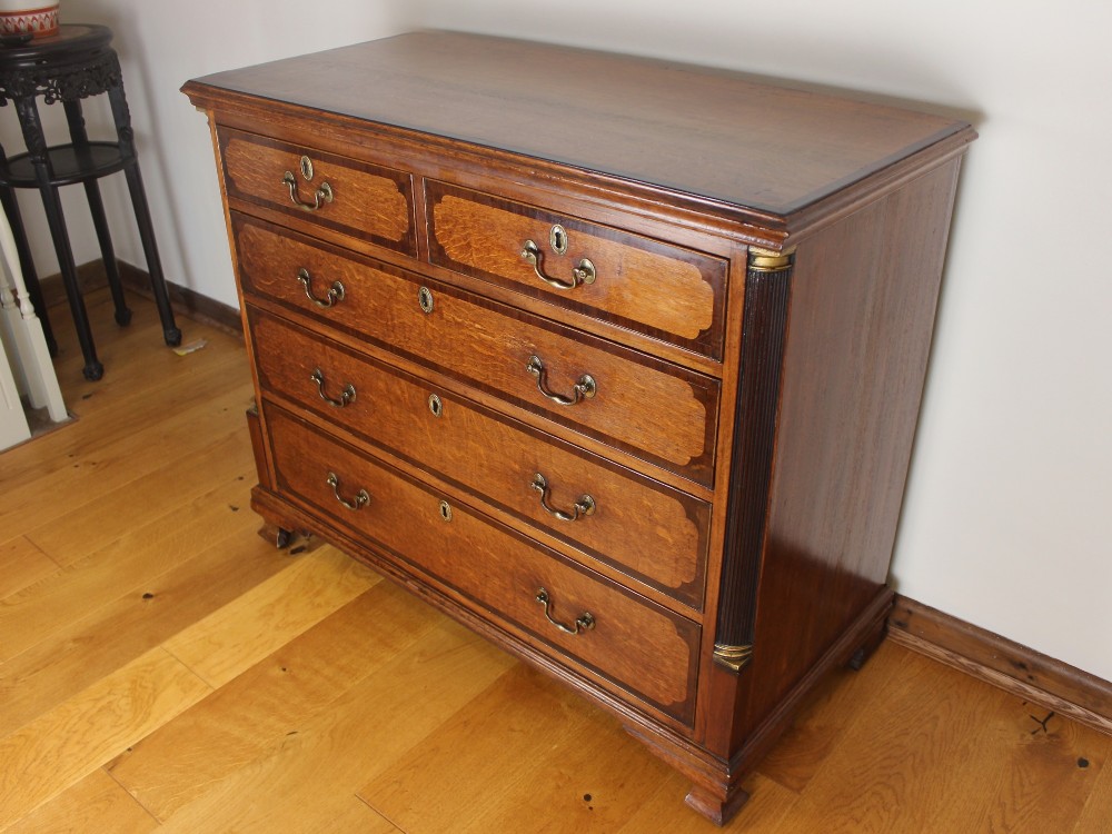 An 18th-century Georgian oak chest of drawers with mahogany crossbanding, brass handles, fluted corner columns, and bracket feet. View IV