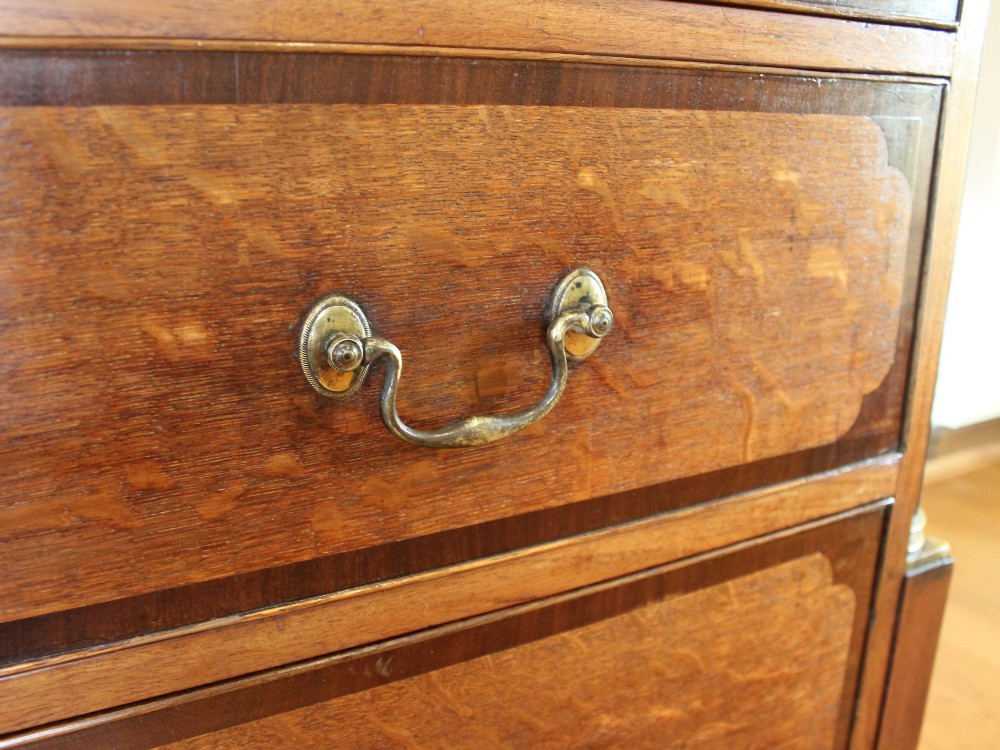 An 18th-century Georgian oak chest of drawers with mahogany crossbanding, brass handles, fluted corner columns, and bracket feet. View V