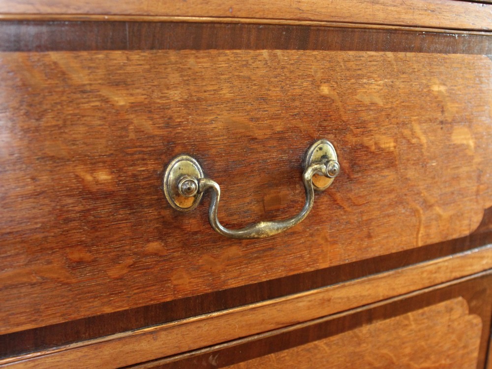 An 18th-century Georgian oak chest of drawers with mahogany crossbanding, brass handles, fluted corner columns, and bracket feet. View VI