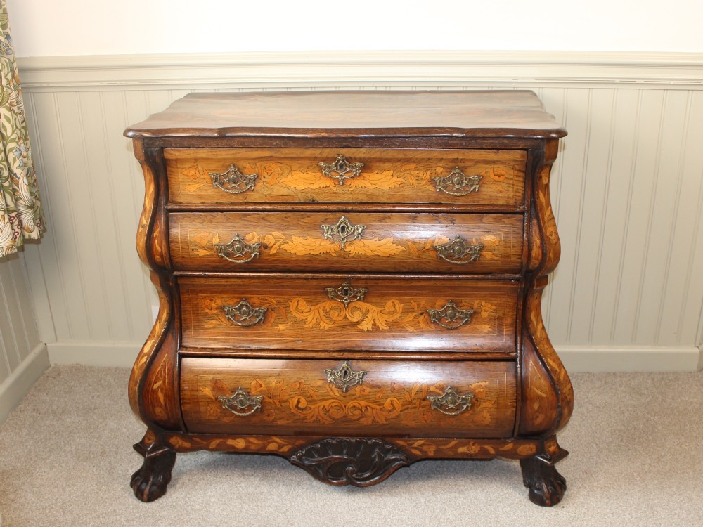 An eighteenth-century Dutch oak chest of drawers featuring a shaped bombe front, elaborate floral marquetry inlay, four graduated drawers with brass handles, and claw and ball feet. View II