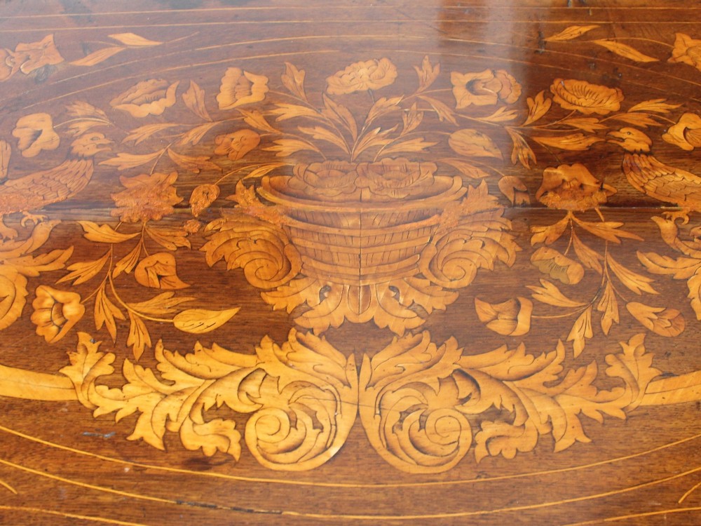 An eighteenth-century Dutch oak chest of drawers featuring a shaped bombe front, elaborate floral marquetry inlay, four graduated drawers with brass handles, and claw and ball feet. View IV