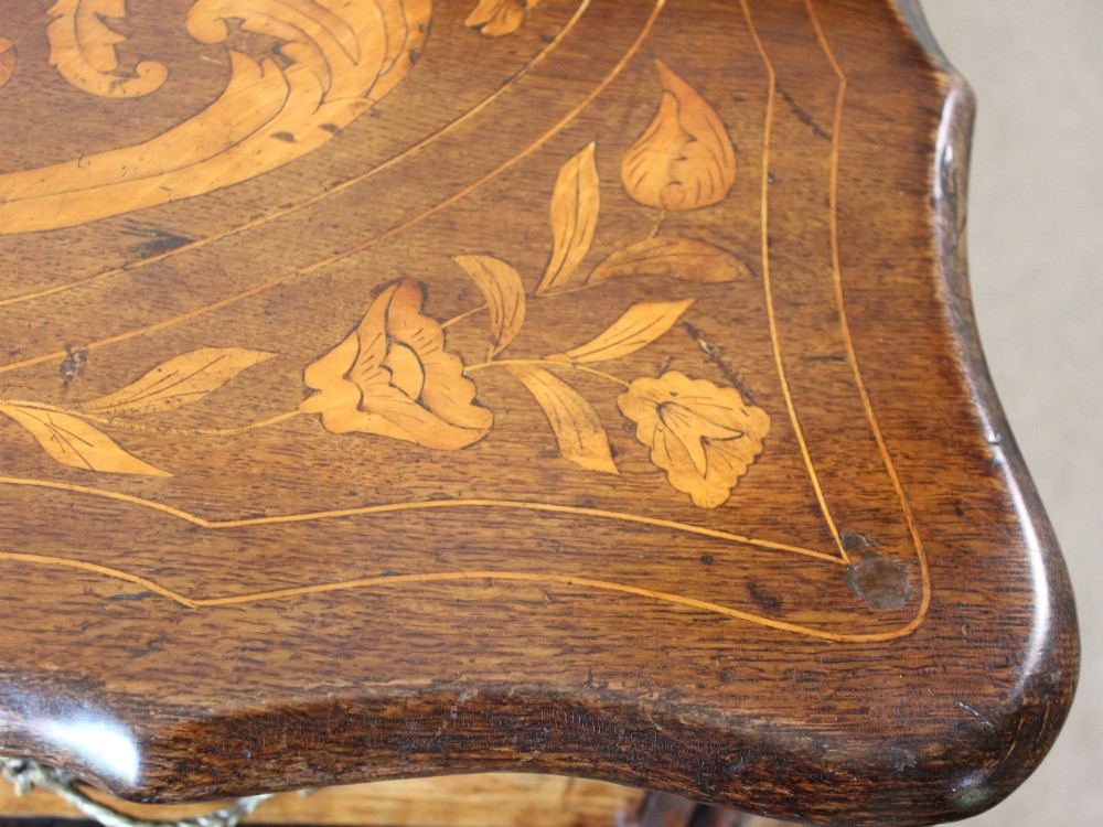 An eighteenth-century Dutch oak chest of drawers featuring a shaped bombe front, elaborate floral marquetry inlay, four graduated drawers with brass handles, and claw and ball feet. View V