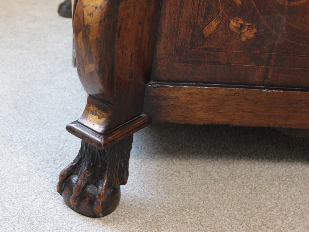 An eighteenth-century Dutch oak chest of drawers featuring a shaped bombe front, elaborate floral marquetry inlay, four graduated drawers with brass handles, and claw and ball feet. View VI