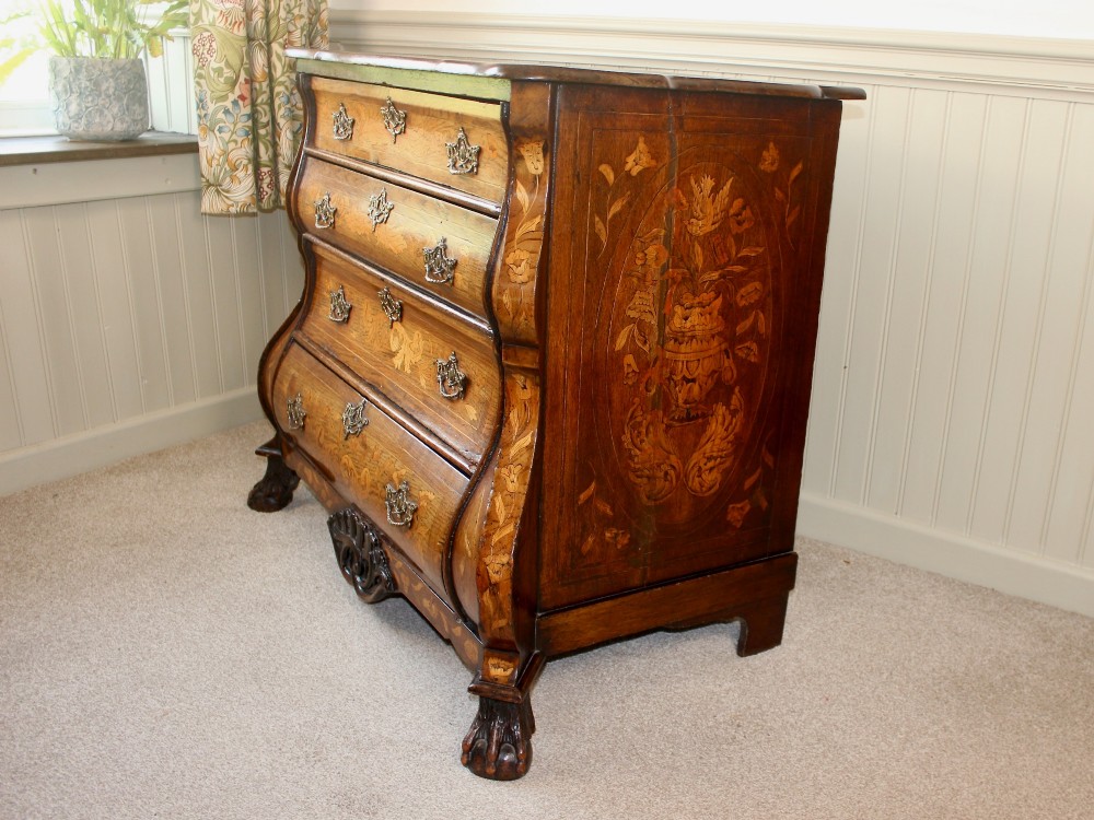 An eighteenth-century Dutch oak chest of drawers featuring a shaped bombe front, elaborate floral marquetry inlay, four graduated drawers with brass handles, and claw and ball feet. View VII