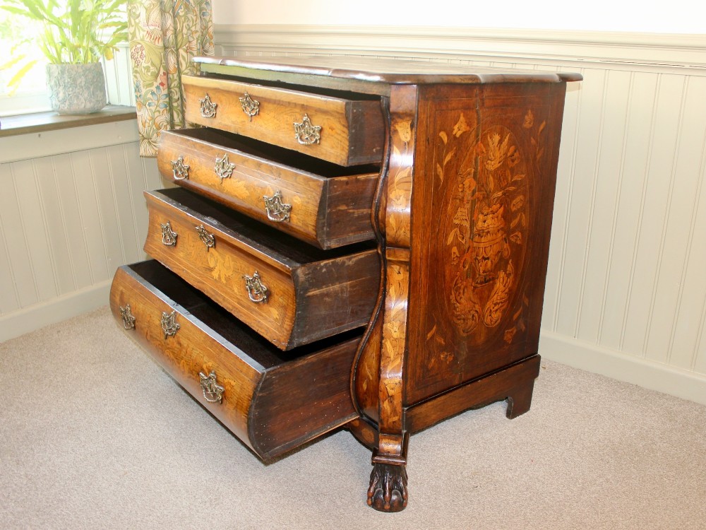 An eighteenth-century Dutch oak chest of drawers featuring a shaped bombe front, elaborate floral marquetry inlay, four graduated drawers with brass handles, and claw and ball feet. View VIII