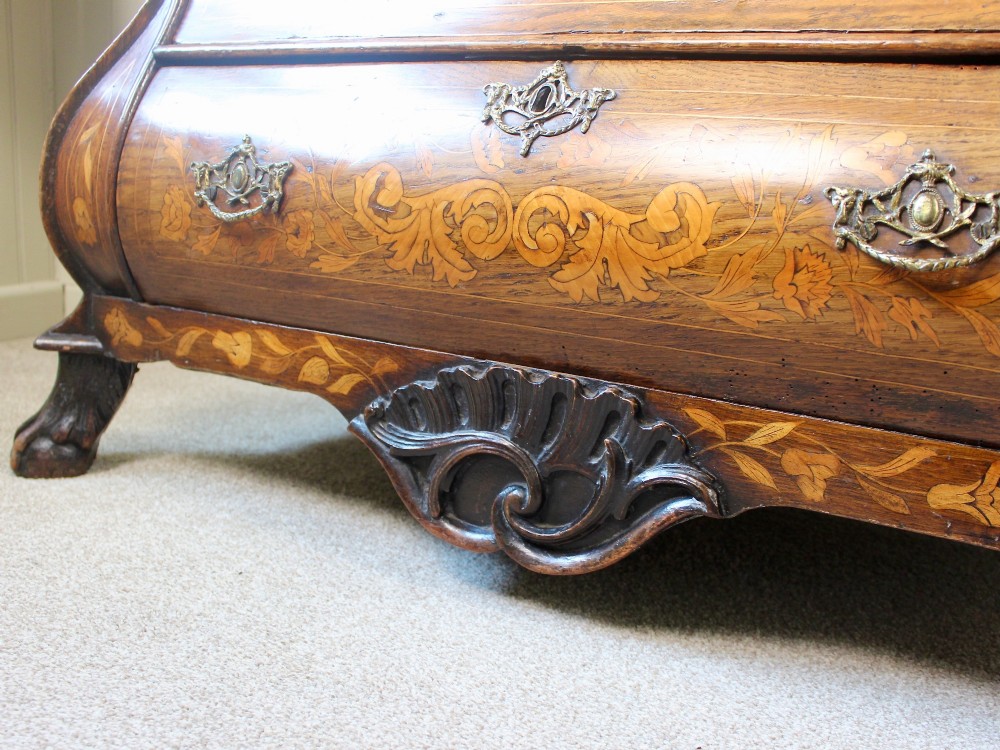 An eighteenth-century Dutch oak chest of drawers featuring a shaped bombe front, elaborate floral marquetry inlay, four graduated drawers with brass handles, and claw and ball feet. View IX