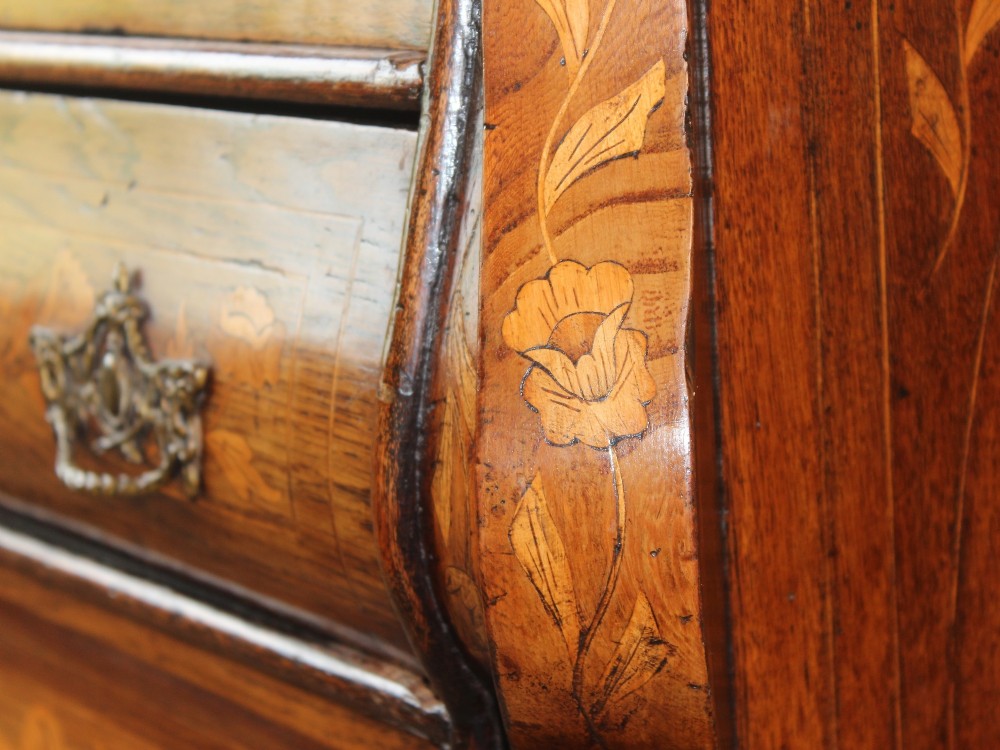 An eighteenth-century Dutch oak chest of drawers featuring a shaped bombe front, elaborate floral marquetry inlay, four graduated drawers with brass handles, and claw and ball feet. View X
