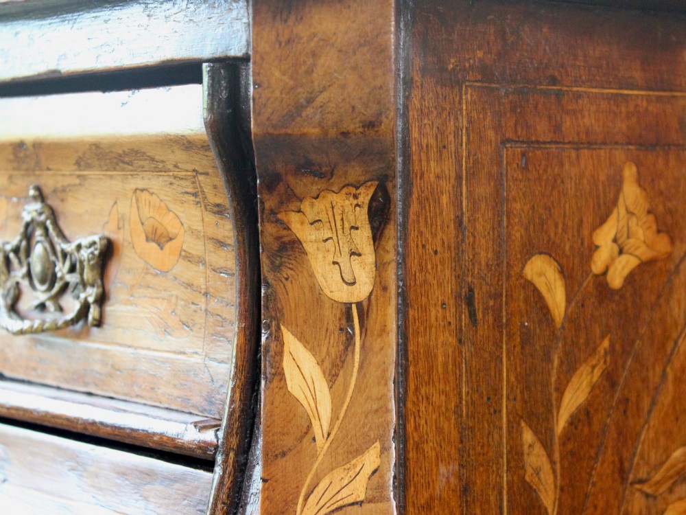 An eighteenth-century Dutch oak chest of drawers featuring a shaped bombe front, elaborate floral marquetry inlay, four graduated drawers with brass handles, and claw and ball feet. View XI