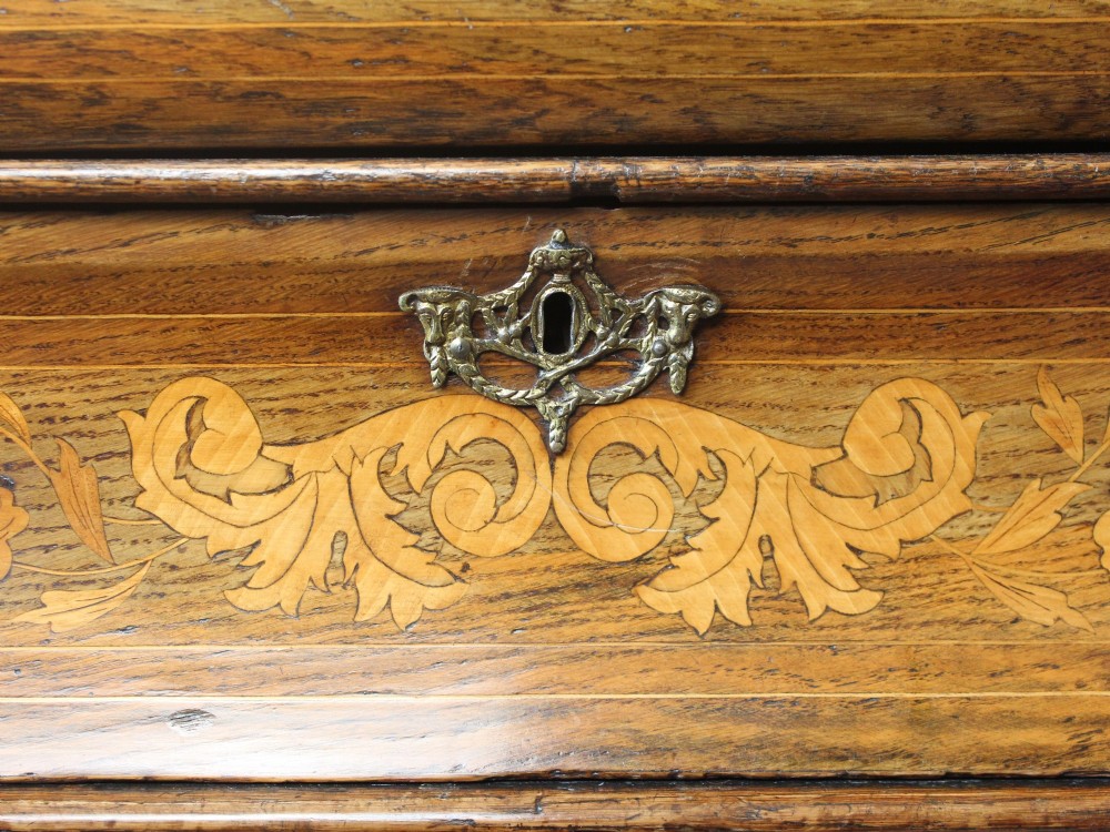An eighteenth-century Dutch oak chest of drawers featuring a shaped bombe front, elaborate floral marquetry inlay, four graduated drawers with brass handles, and claw and ball feet. View XIII