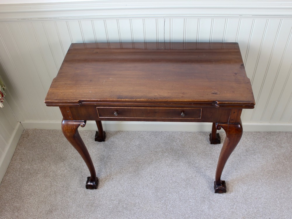 A George III mahogany fold-over card table featuring cabriole legs terminating in ball and claw feet alongside a central frieze drawer. View III