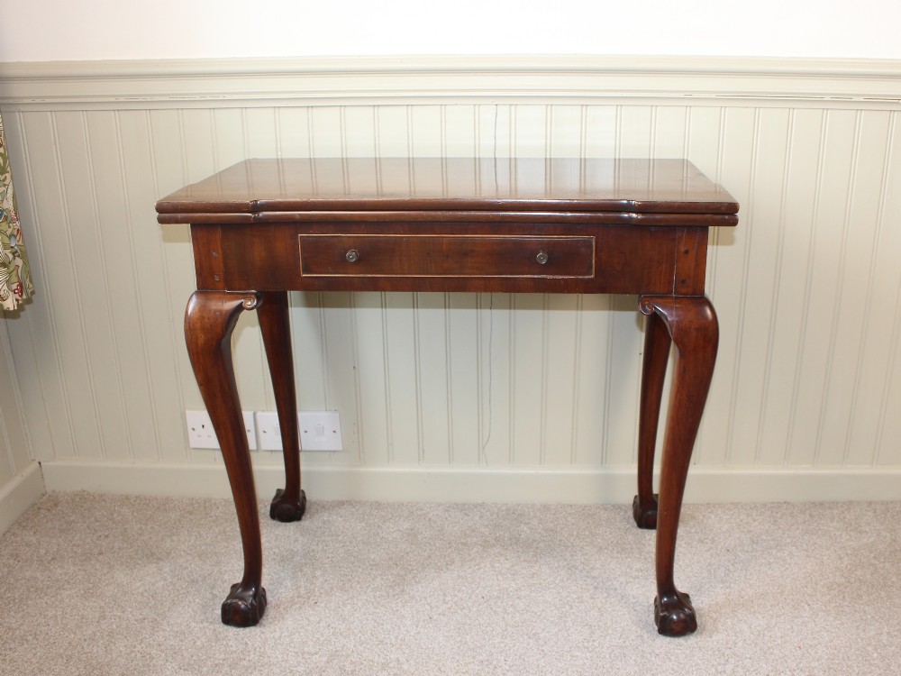 A George III mahogany fold-over card table featuring cabriole legs terminating in ball and claw feet alongside a central frieze drawer. View IV