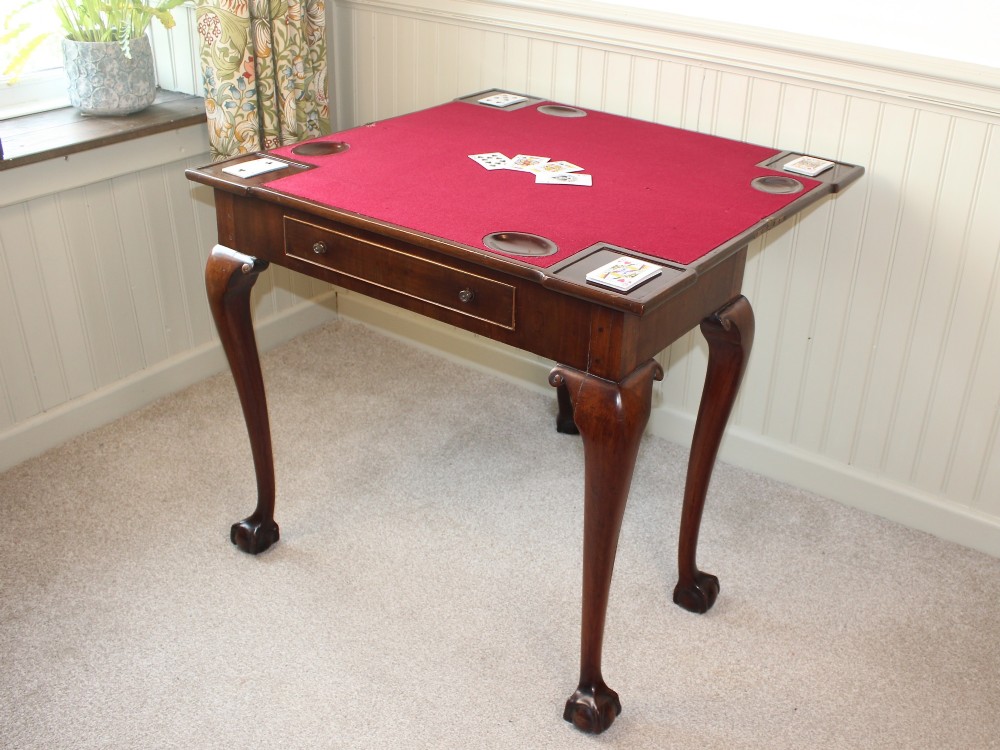 A George III mahogany fold-over card table featuring cabriole legs terminating in ball and claw feet alongside a central frieze drawer. View V