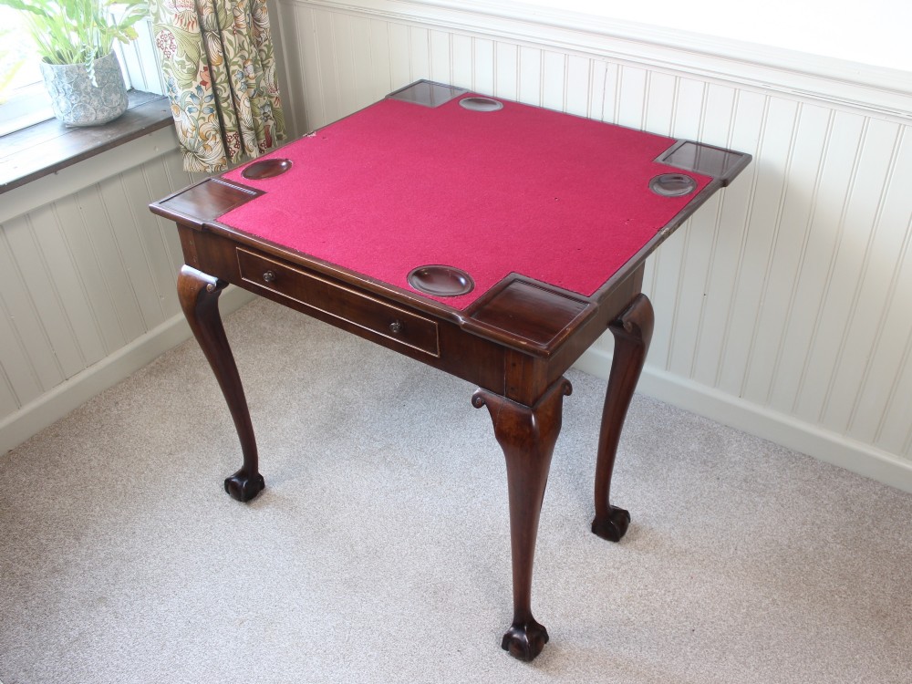 A George III mahogany fold-over card table featuring cabriole legs terminating in ball and claw feet alongside a central frieze drawer. View VII
