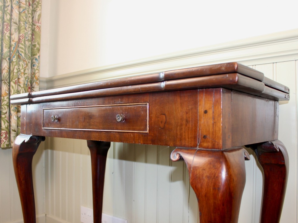 A George III mahogany fold-over card table featuring cabriole legs terminating in ball and claw feet alongside a central frieze drawer. View IX