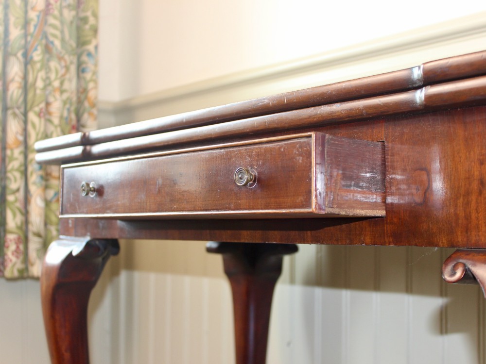 A George III mahogany fold-over card table featuring cabriole legs terminating in ball and claw feet alongside a central frieze drawer. View XI