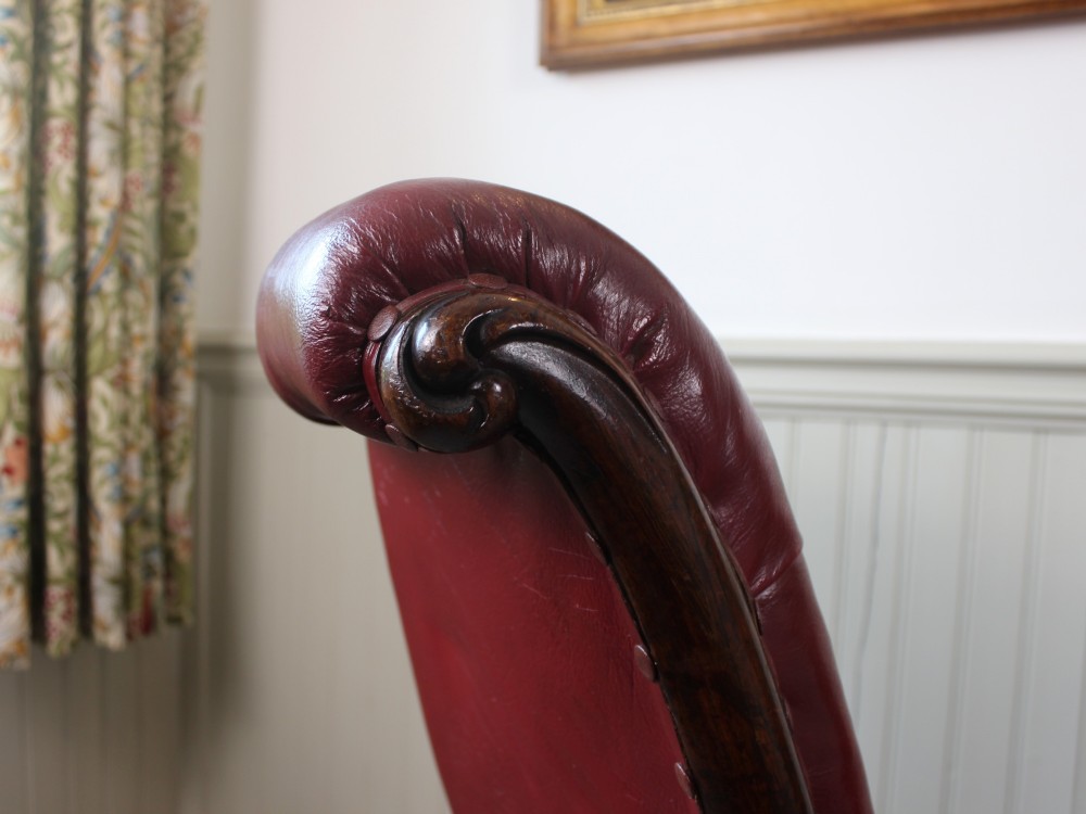 An early Victorian slipper chair featuring deep-buttoned red leather upholstery, a rosewood frame, and turned front legs on brass castors. View IV